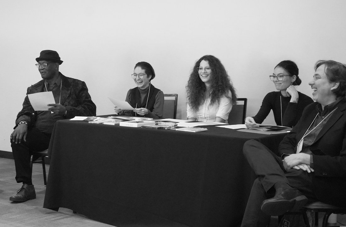 Black and white photo of people seated in a semi circle.