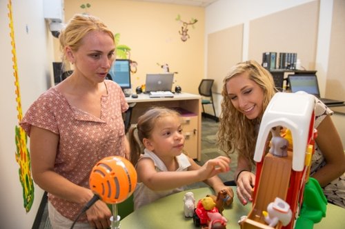 two female researchers with a female child in the lab