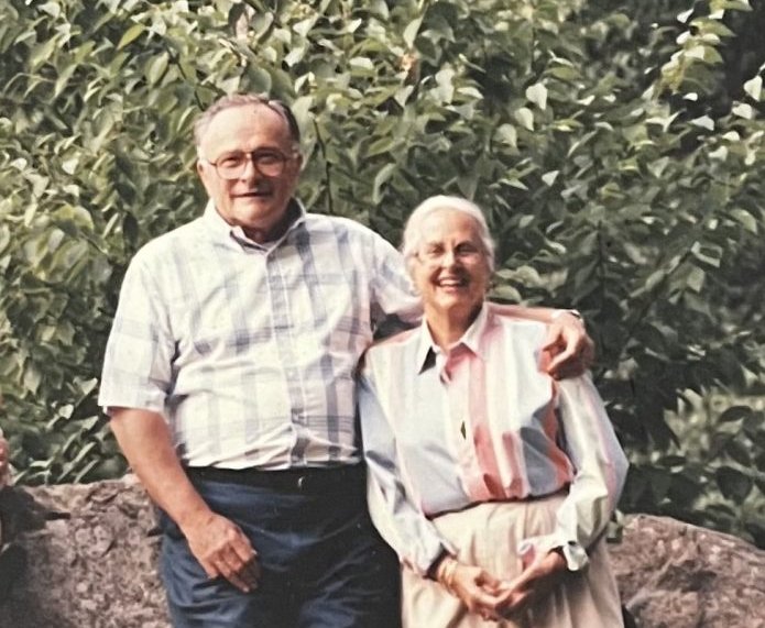 Two people standing in front of a rock.