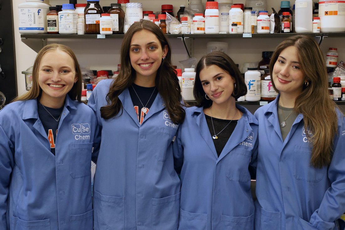 Four women standing in a row in lab coats.