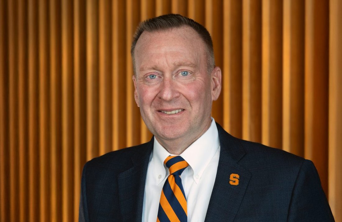 Man wearing a suit and an orange and blue striped tie.