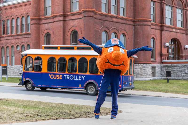 Syracuse Orange in front of a campus trolley and Tolley hall