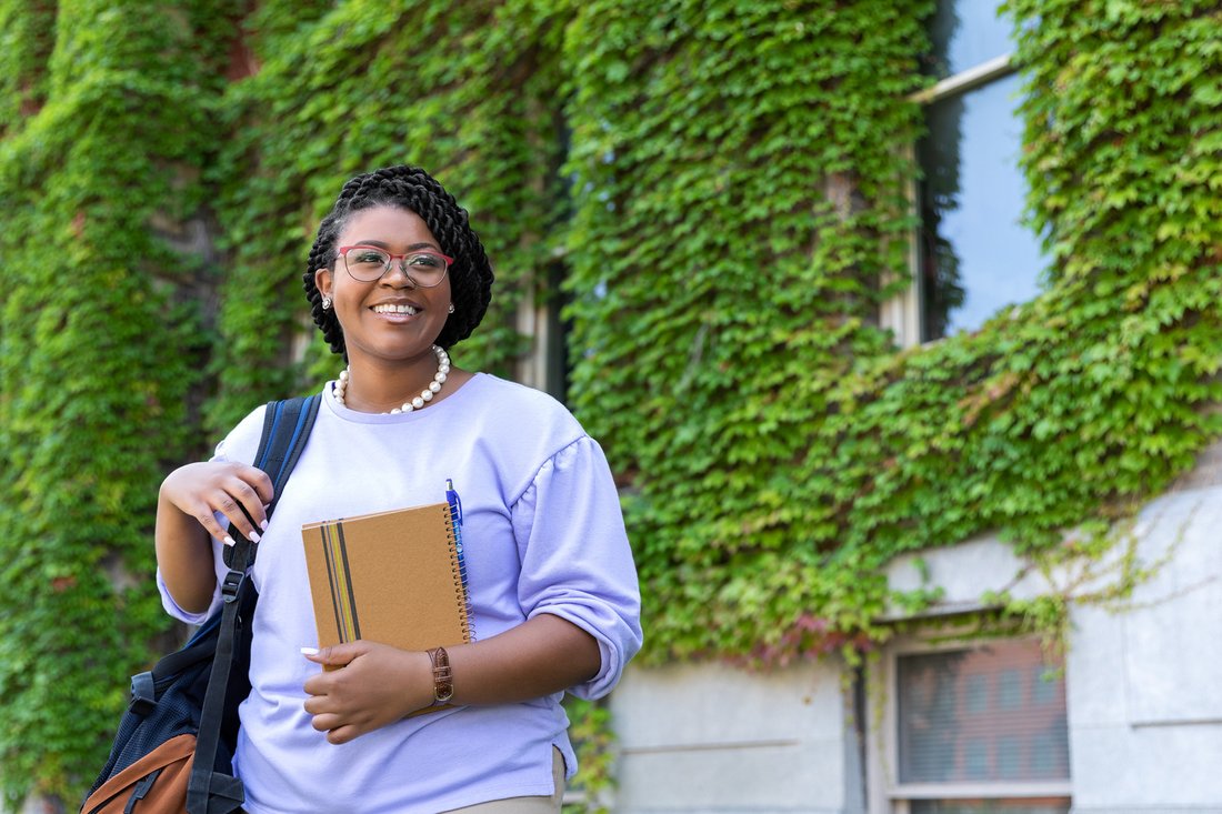 A student in front of an ivy covered building