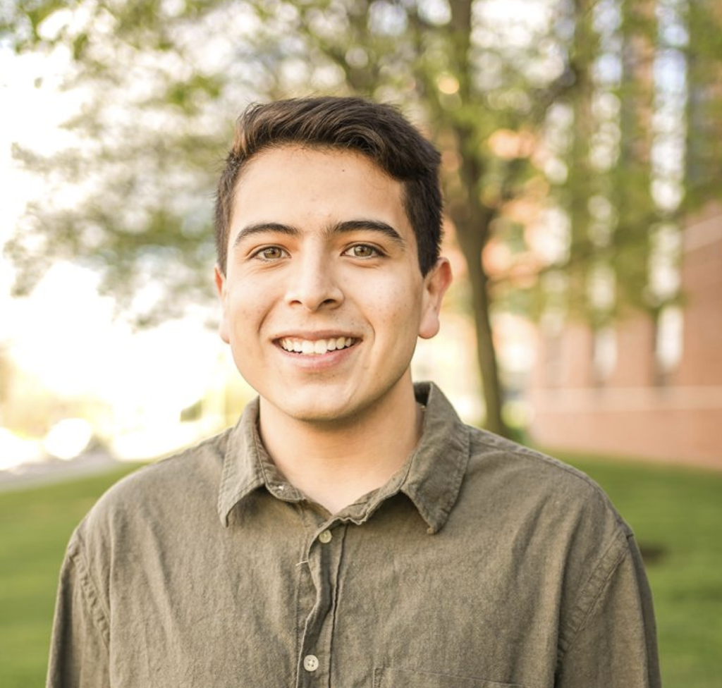 A student researcher in front of trees