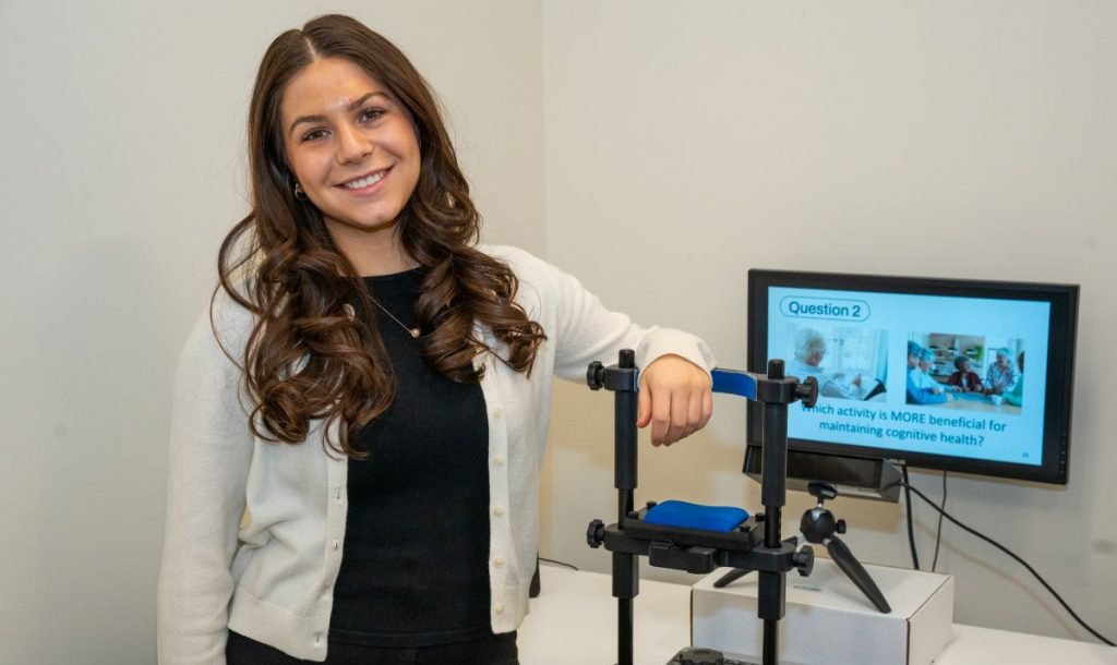 Person standing in front of a computer and speech therapy equipment.