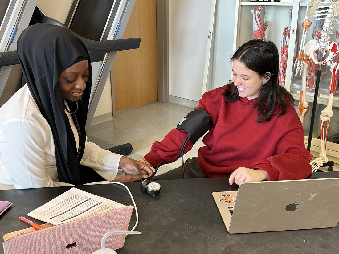 One student takes another's blood pressure in a classroom lab