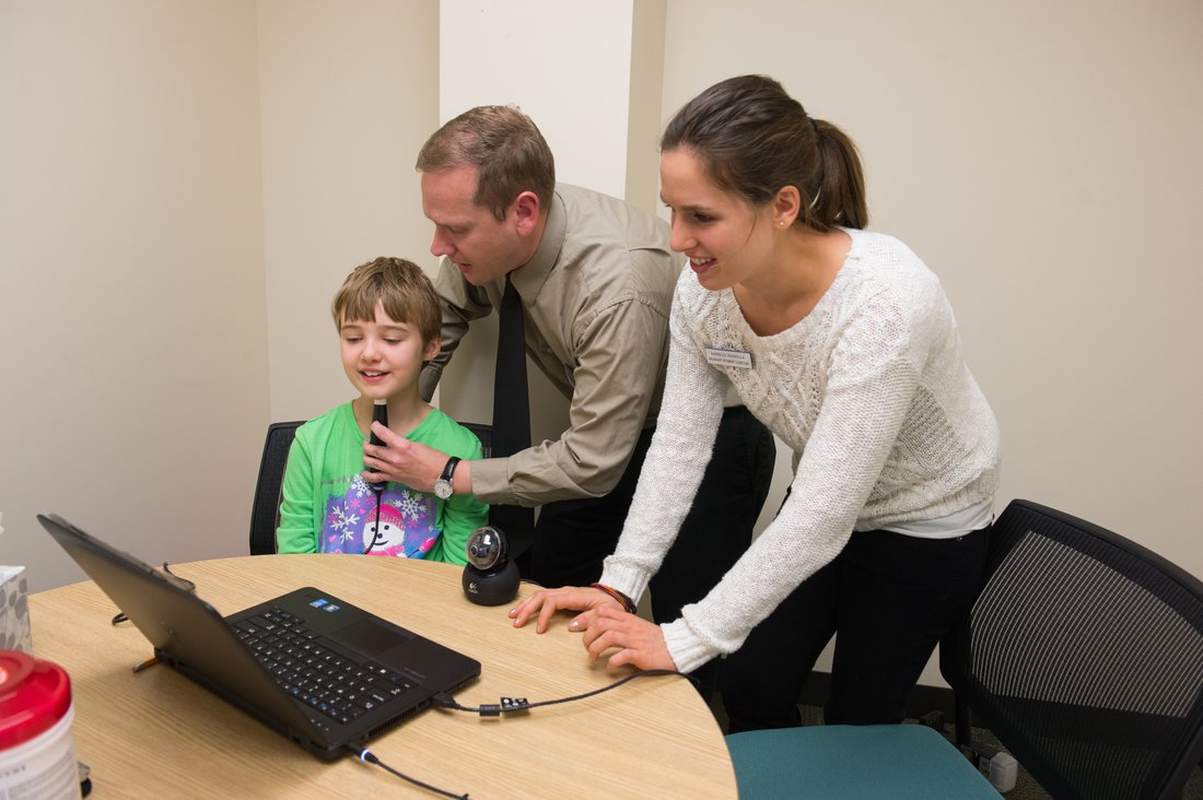 Two adults conducting speech research with a child.