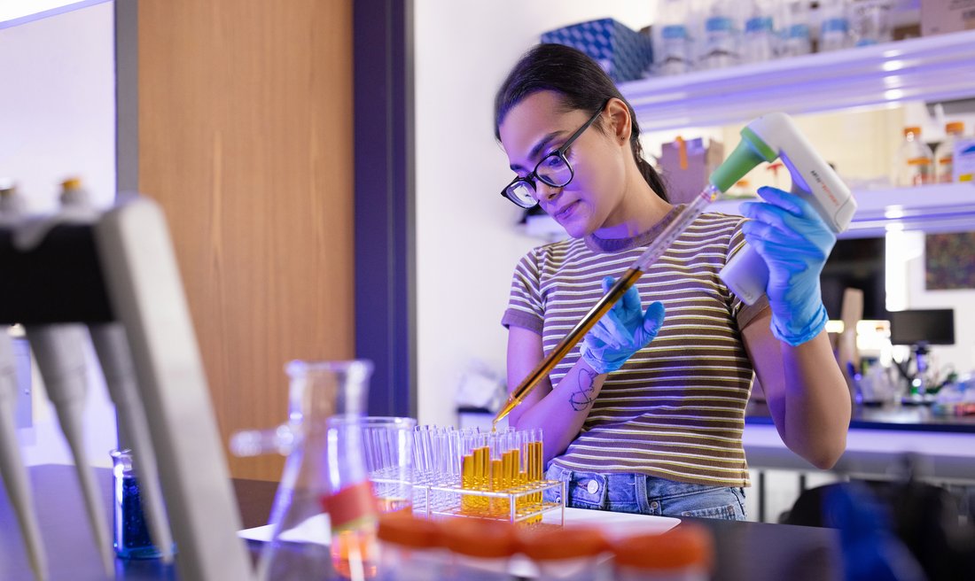Person pouring liquid into vials.