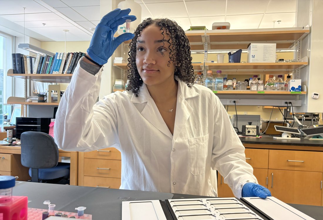student inspecting a vial in a lab