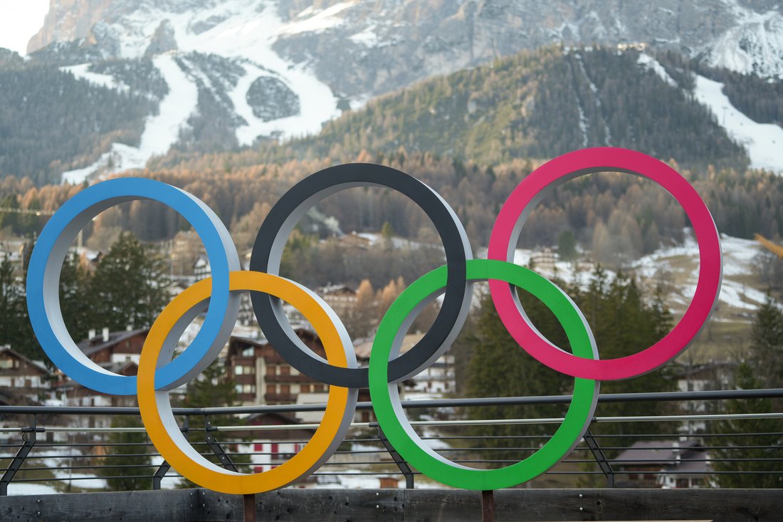 Olympic ring statue in front of a mountain.