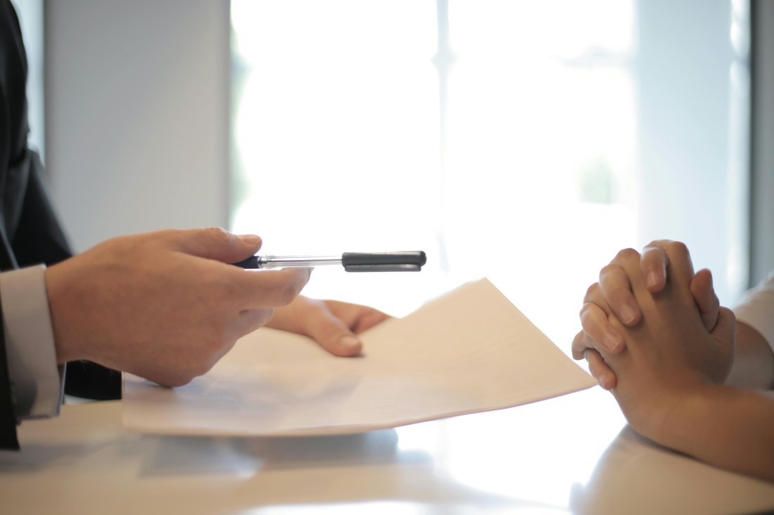 Person handing another person a form.