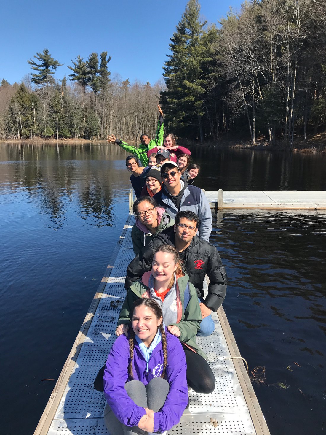 Students posing for picture on a dock on a lake.