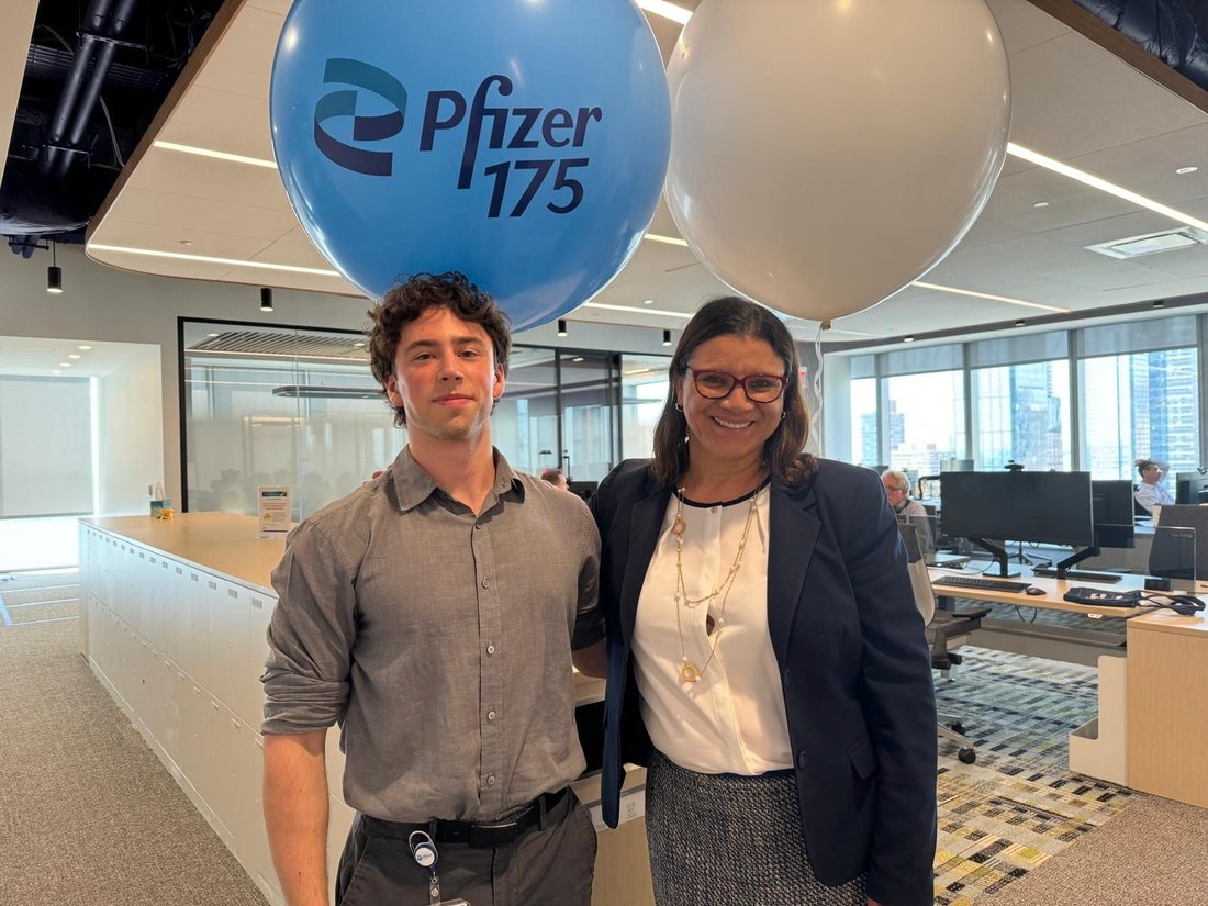 Two people posing for a photo in front of two balloons.
