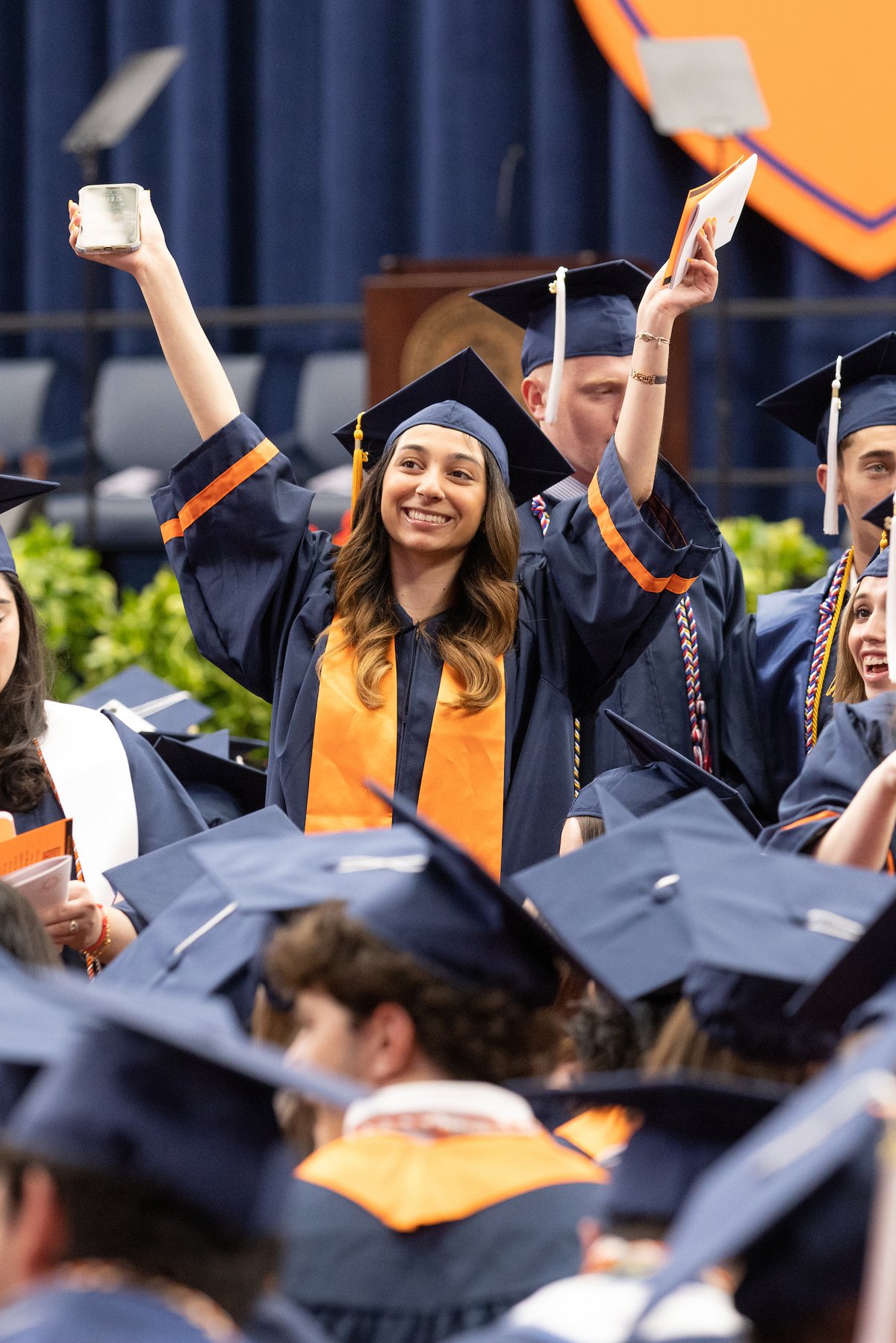 Hands in the air, a student celebrates her graduation.