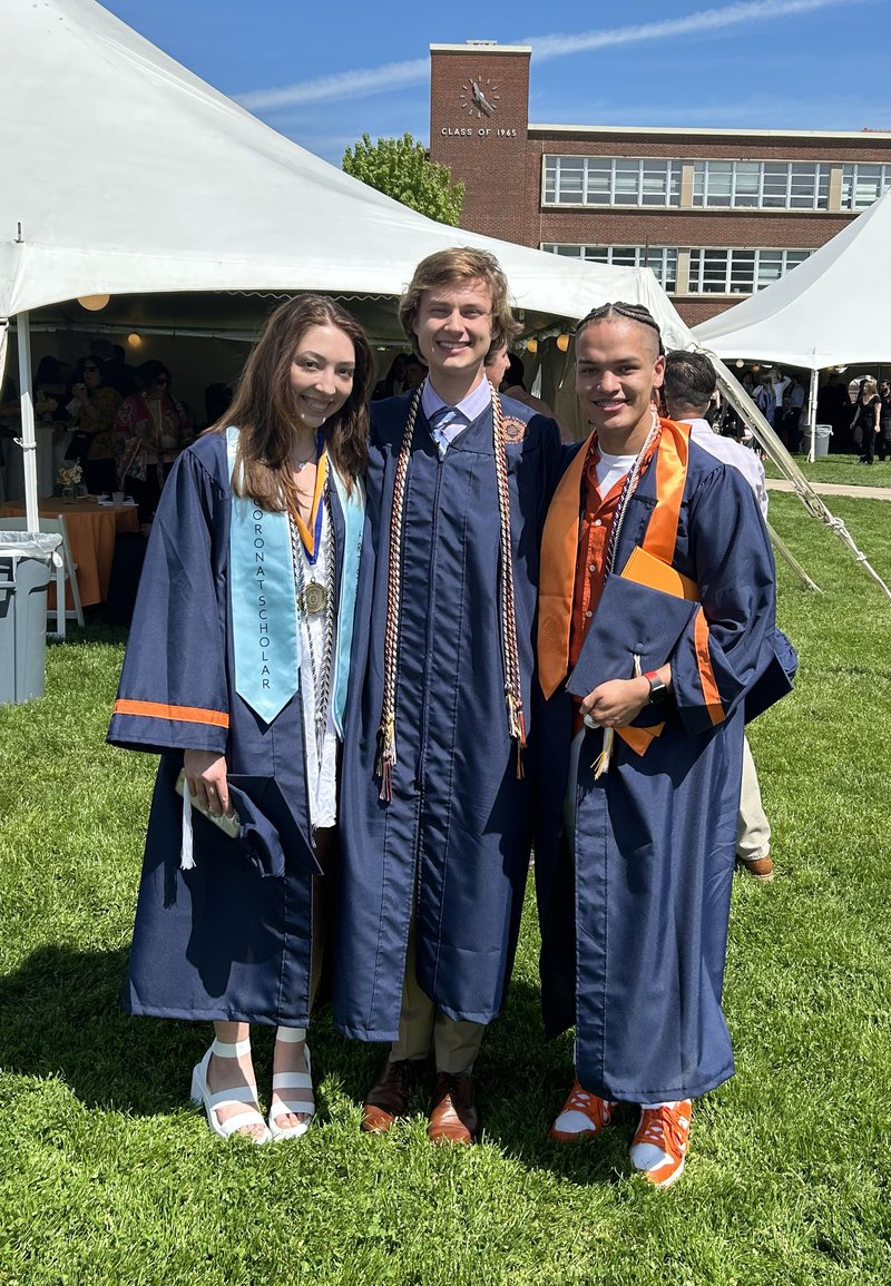 Three students in graduation gowns posing for a photo.