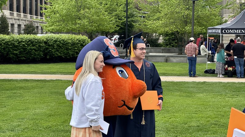 Student and a family member pose for a photo with Otto after convocation 2024