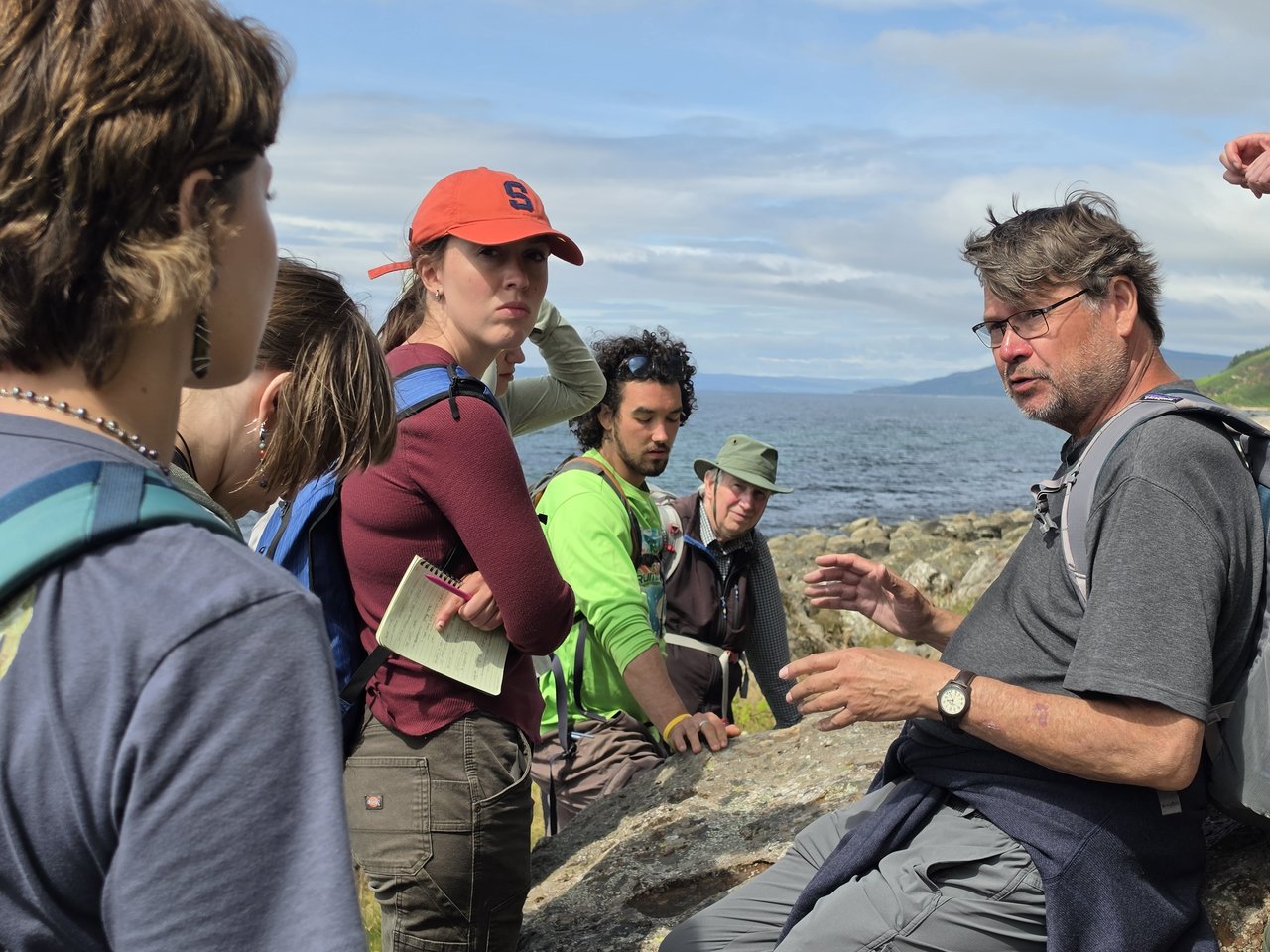 Person explaining something to others against the backdrop of the sea.