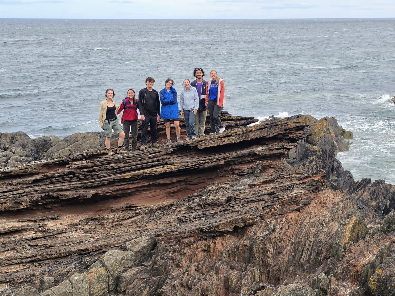 Group of people standing on top of the famous Siccar Point unconformity.