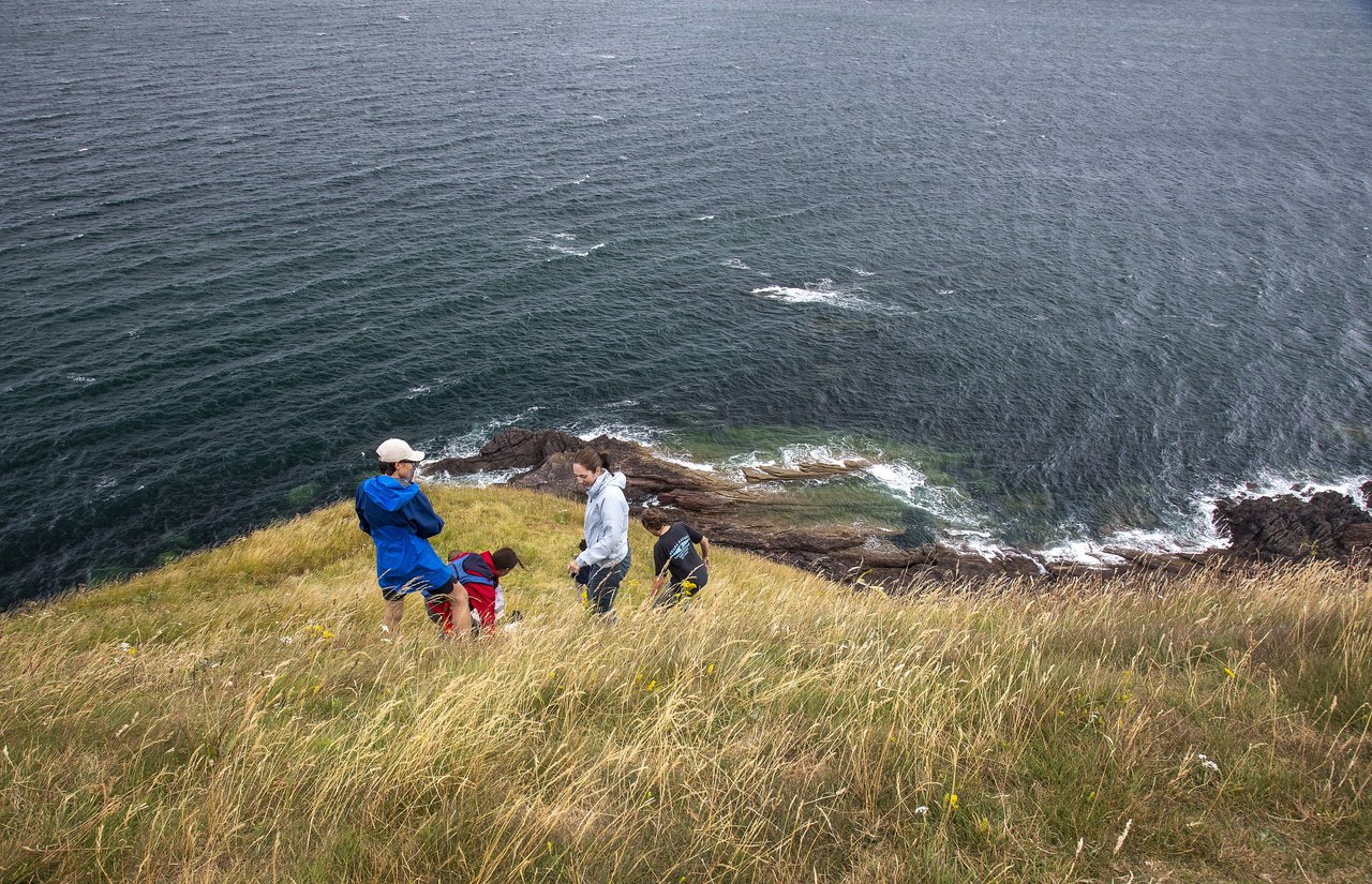 People walking down a cliff toward water.