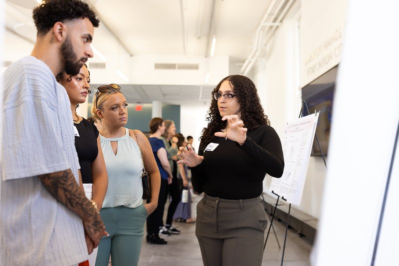 Student presenting a poster to other students