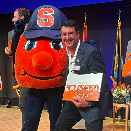 Person holding an award standing with Otto the Orange mascot.