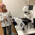 Woman providing a demonstration with a microscope.