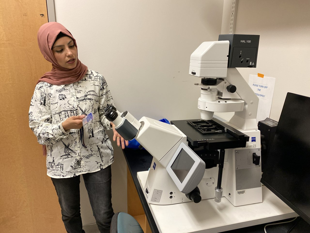 Woman providing a demonstration with a microscope.