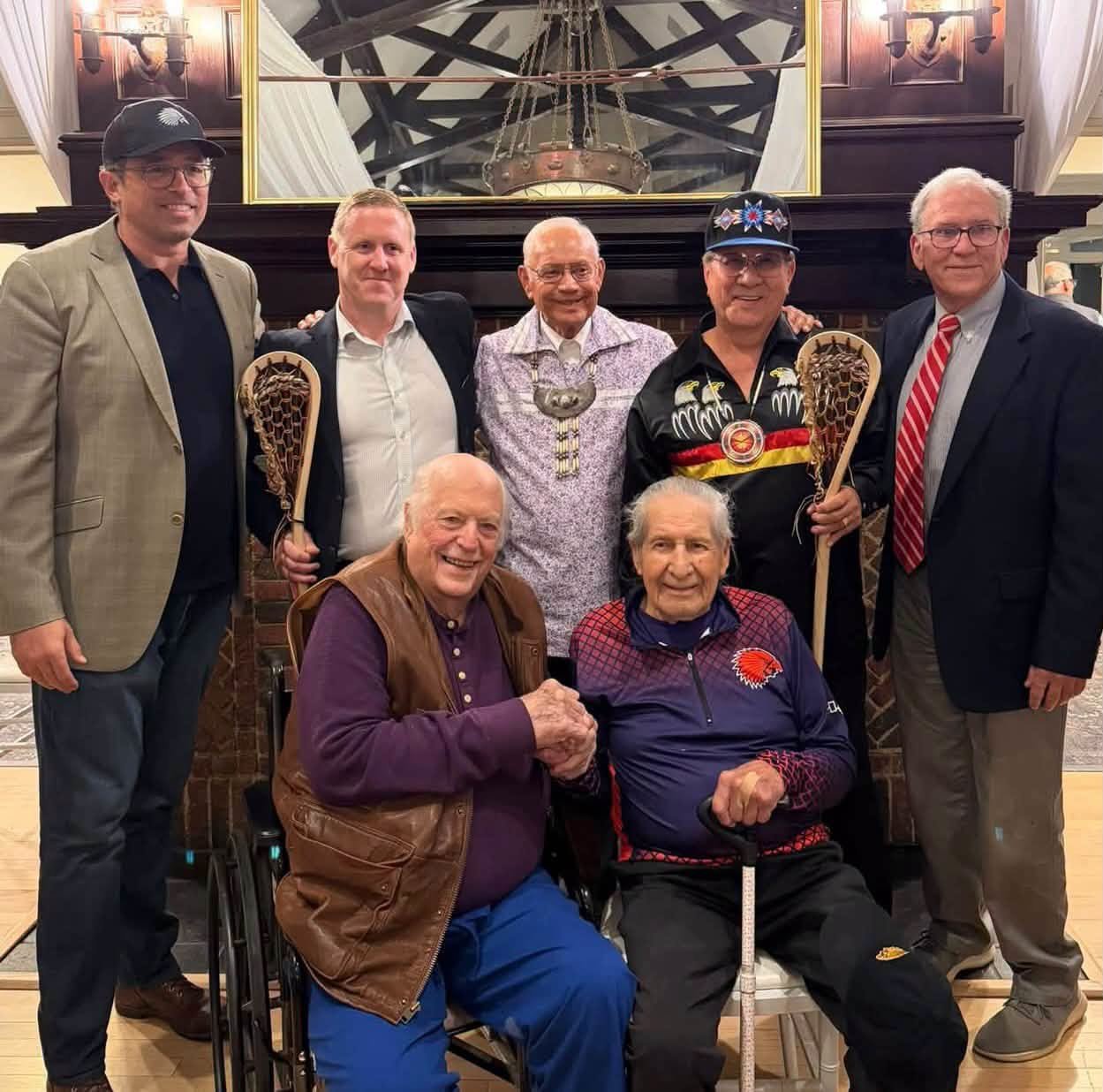 Group of people with two holding lacrosse sticks.