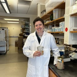 A person in a lab holding a jar of sourdough starter.