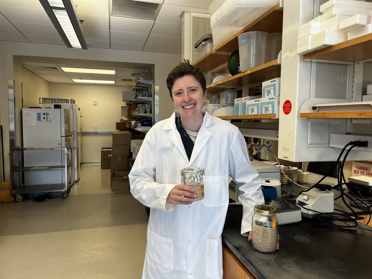 A person in a lab holding a jar of sourdough starter.