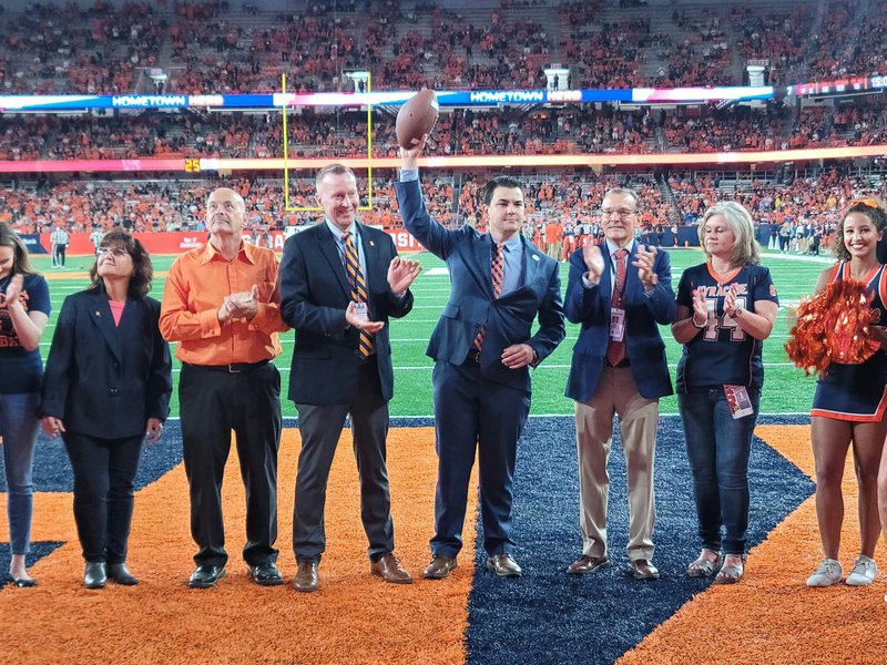 Anthony Ruscitto holding a football with a group of people around him.