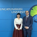 Two people standing in front of a wall with text that reads Sungkyunkwan University