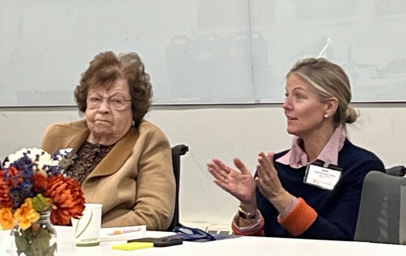 Two women sitting together at a table during a meeting.