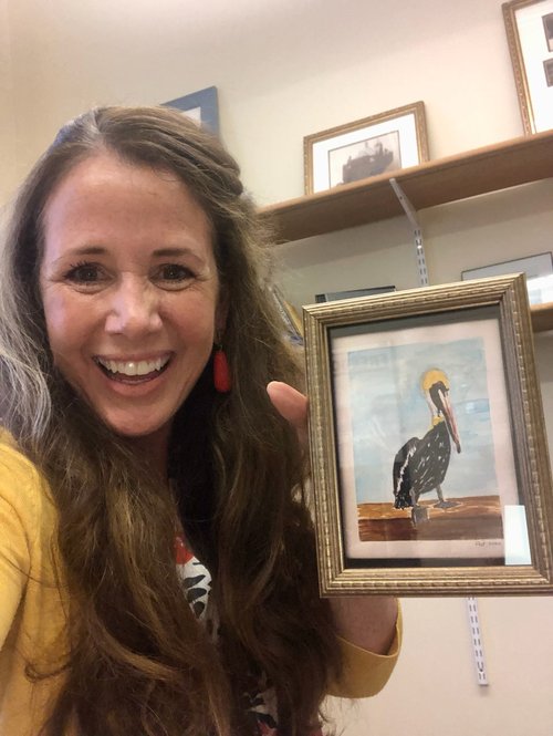 Person holding a painting of a pelican.