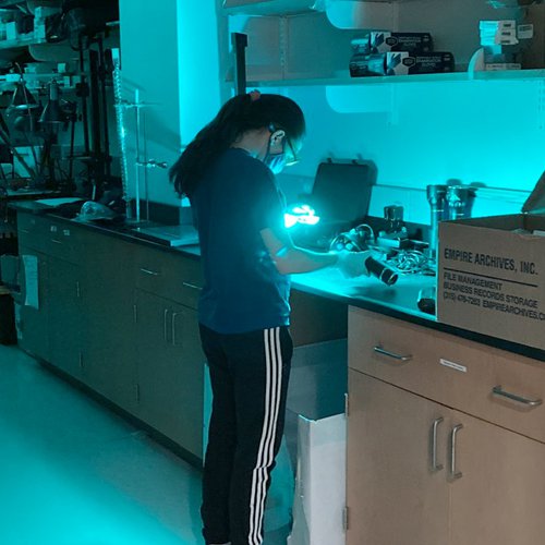 Syracuse University student using blue light to inspect evidence.