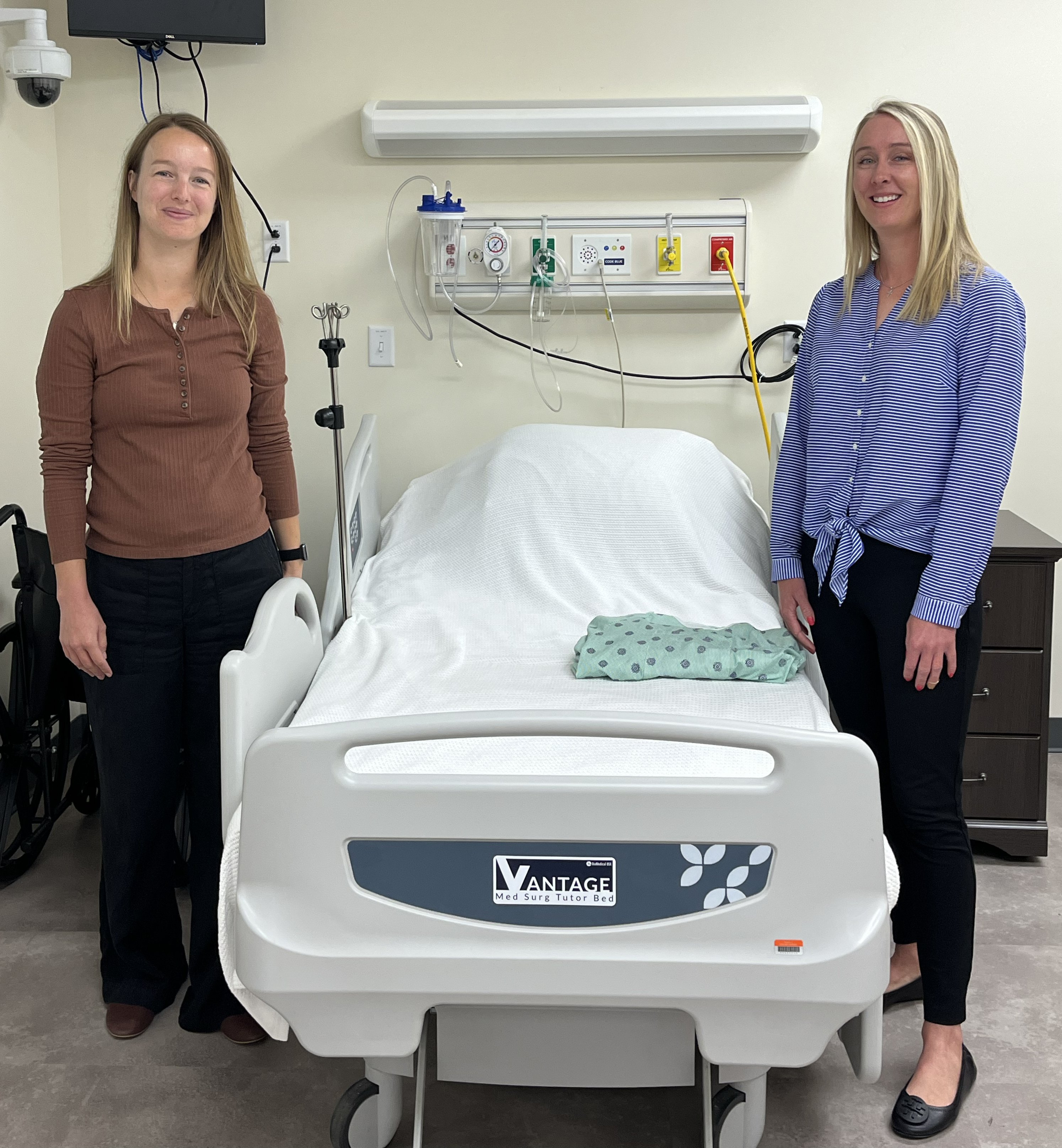 Two people standing beside a hospital bed.