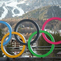 Olympic ring statue in front of a mountain.