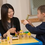An adult playing with a child during therapy session.