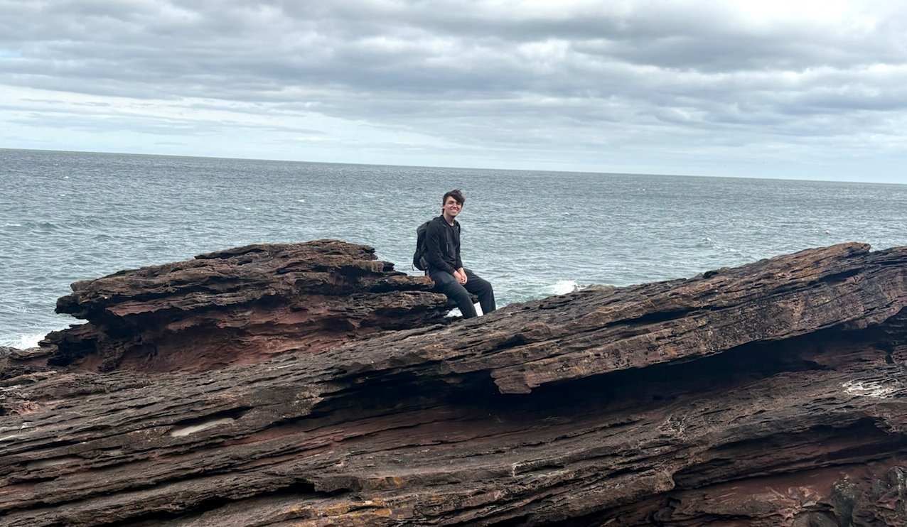 Person sitting on top of a rock outcrop.