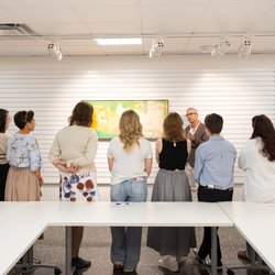 Group of students watching someone discuss an art work.