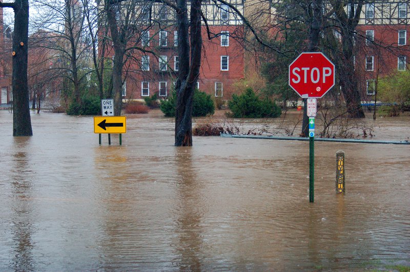 Flooded roadway with stop sign and building in the background.