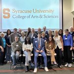 Group of people standing in front of a screen with College of Arts and Sciences lockup graphic.