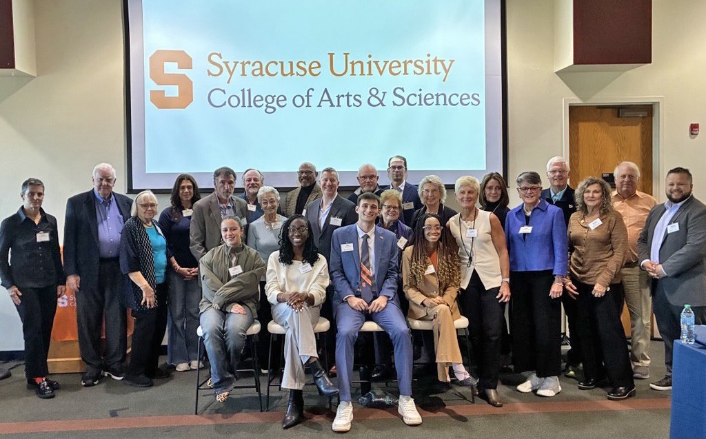 Group of people standing in front of a screen with College of Arts and Sciences lockup graphic.