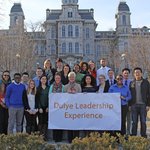 Group of people standing in front of Hall of Languages holding a sign that sayd Dulye Leadership Experience.