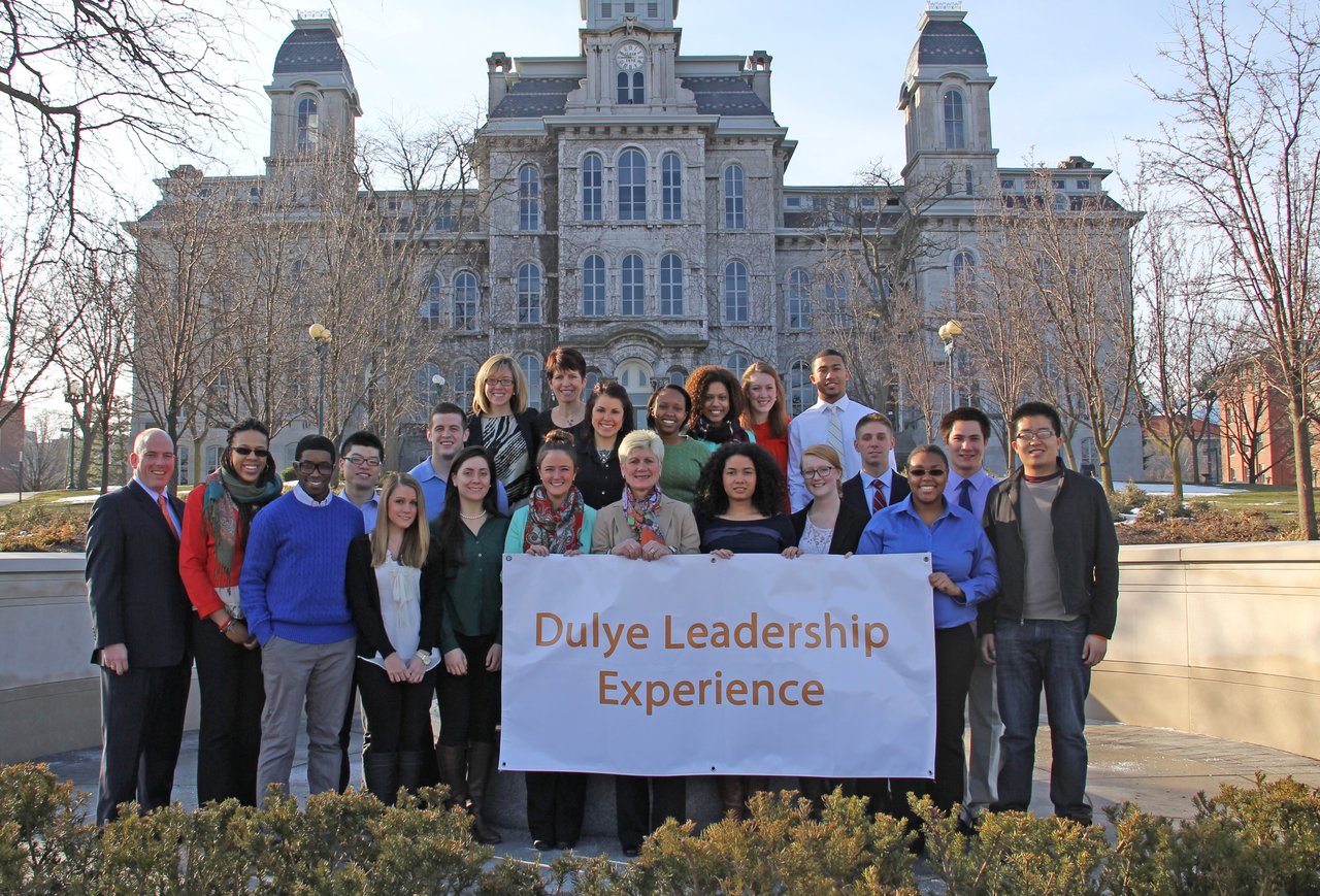 Group of people standing in front of Hall of Languages holding a sign that sayd Dulye Leadership Experience.