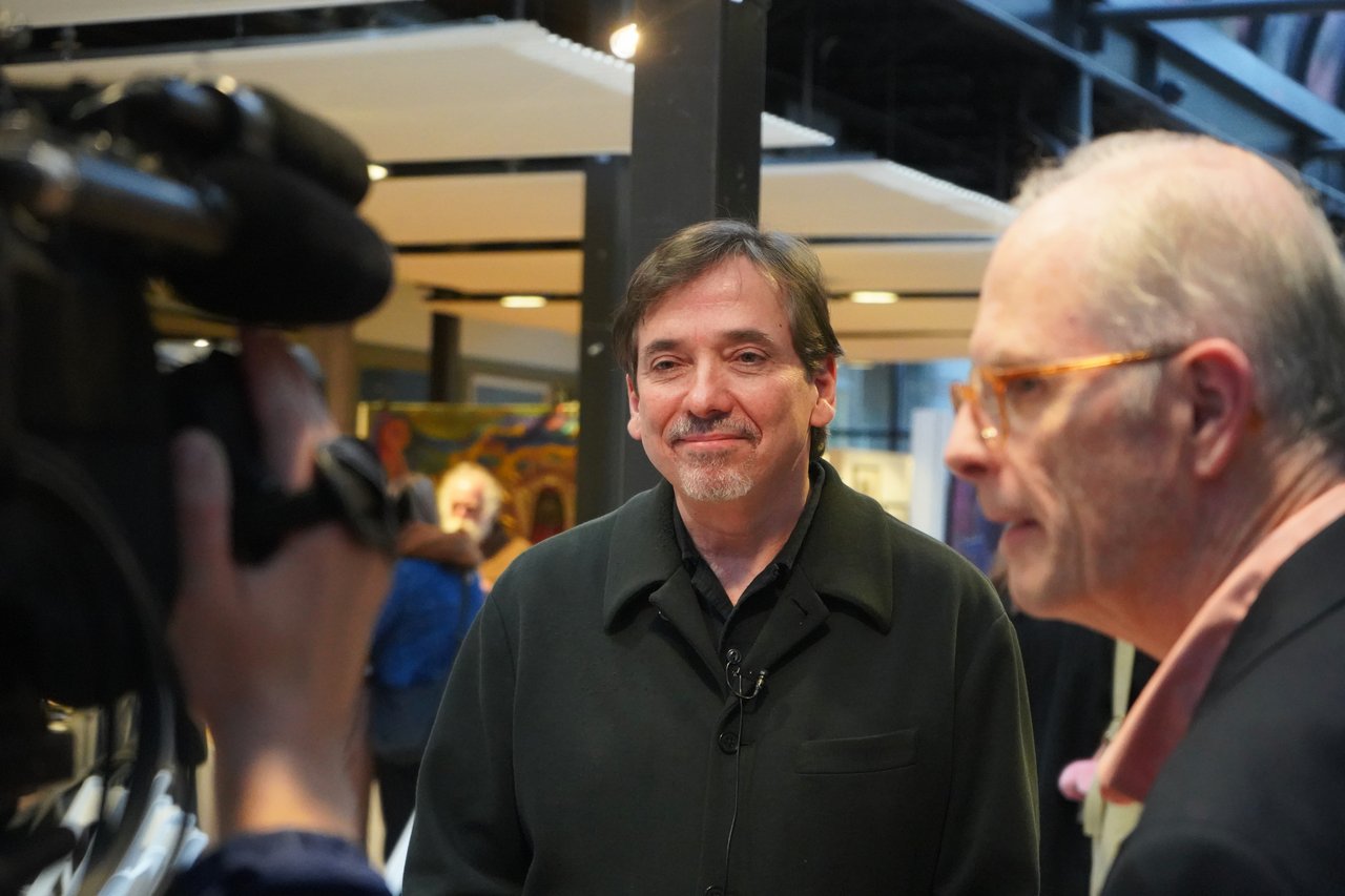 Person being interviewed by a reporter and person with a video camera.