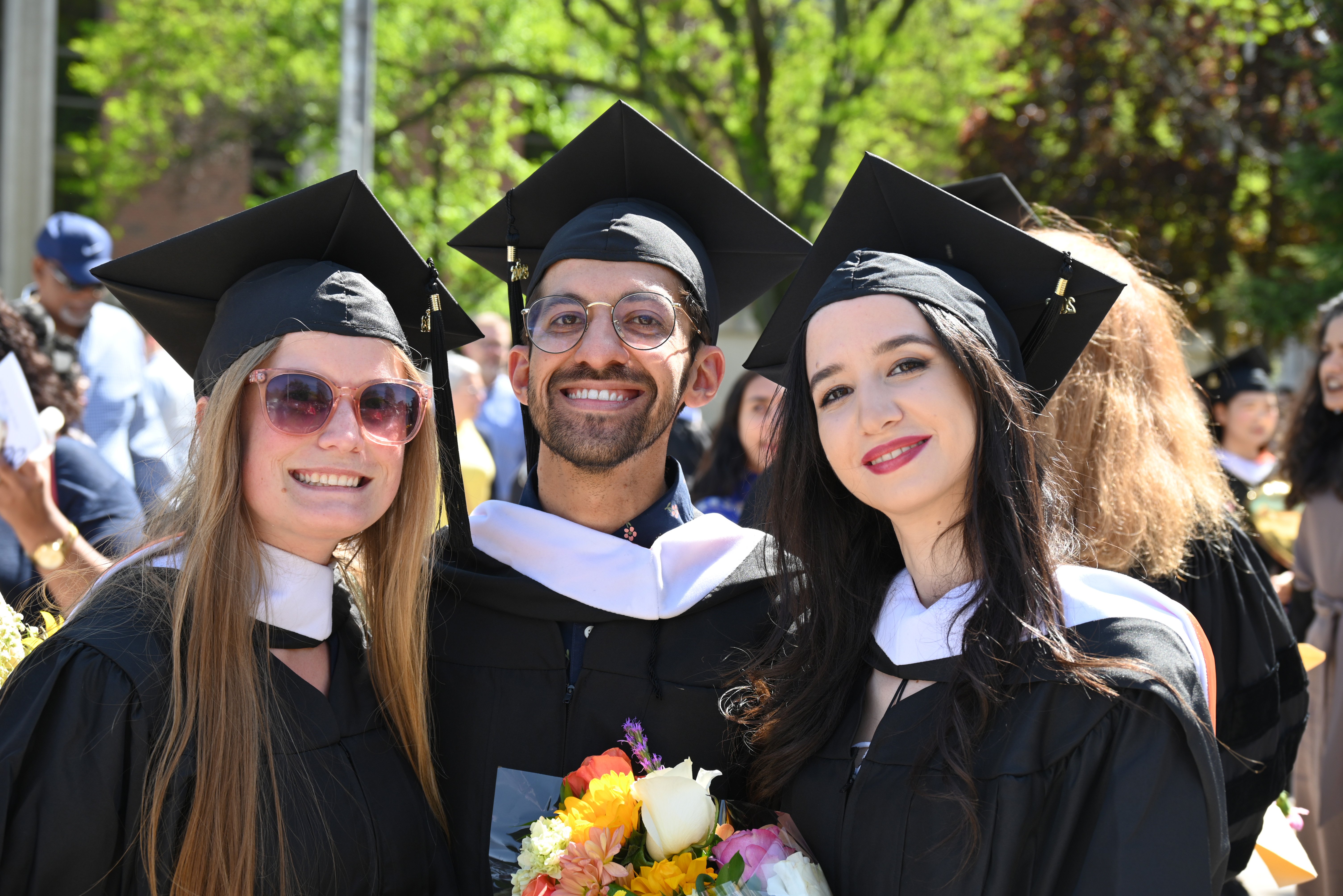 Three students posing for a photo following Commencement.