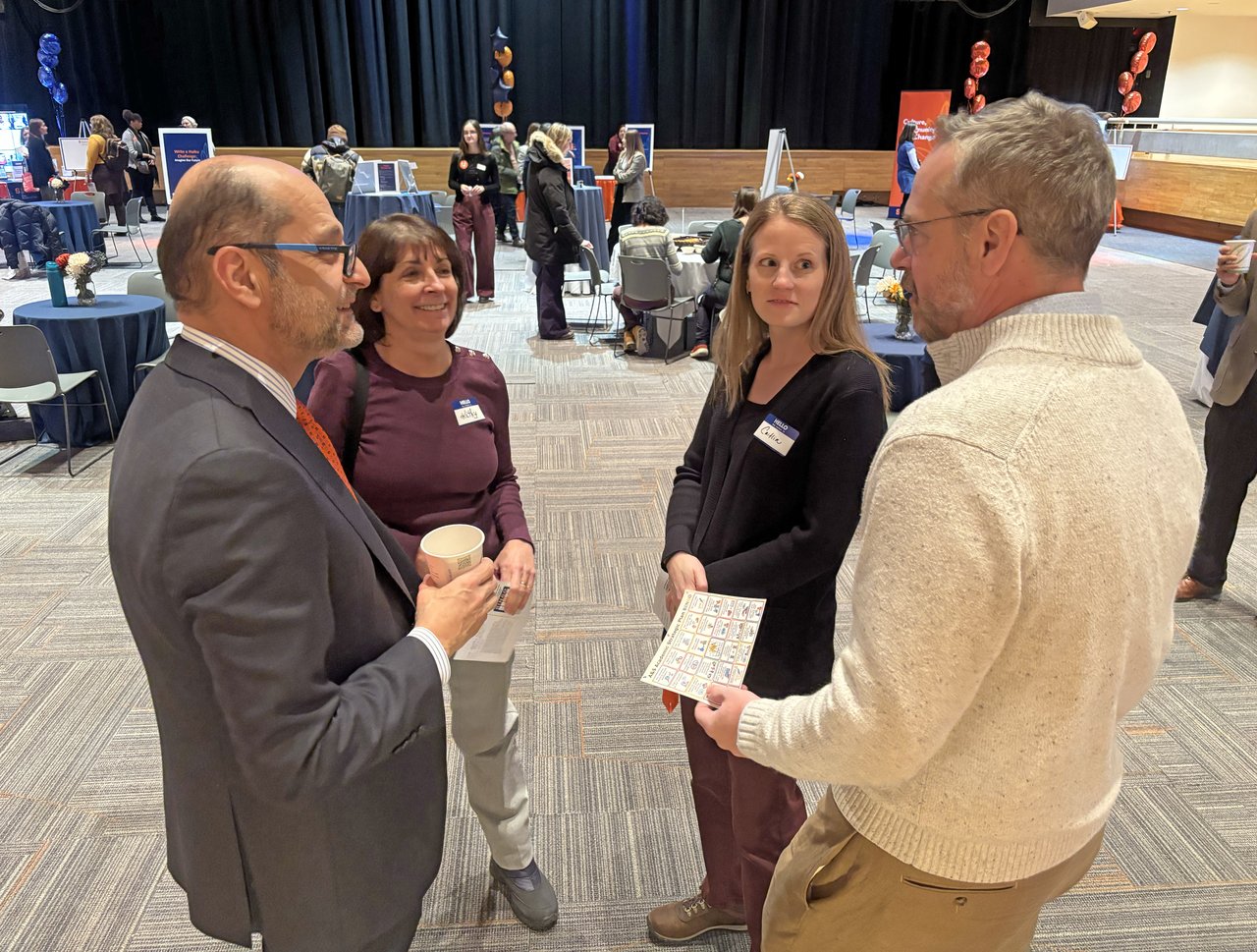 Four people talking standing in a large room.