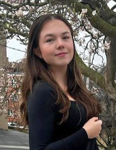 Person in a black shirt standing in front of a tree.