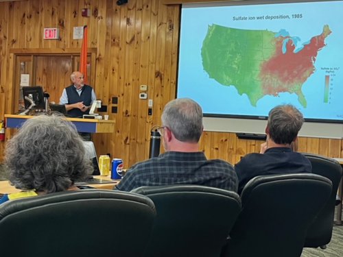 Person standing at a podium addressing a group.